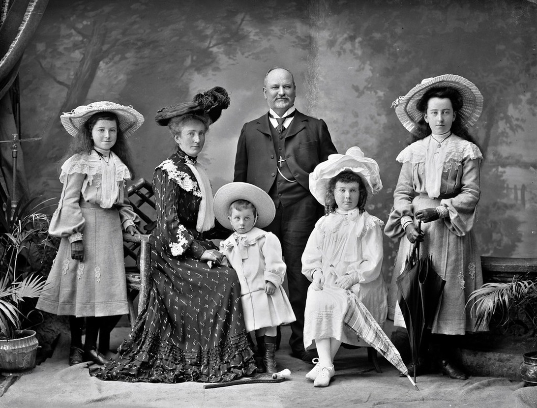 Ein formelles Familienporträt aus dem viktorianischen Ära mit mehreren Generationen und Kindern in aufwendiger Kleidung.