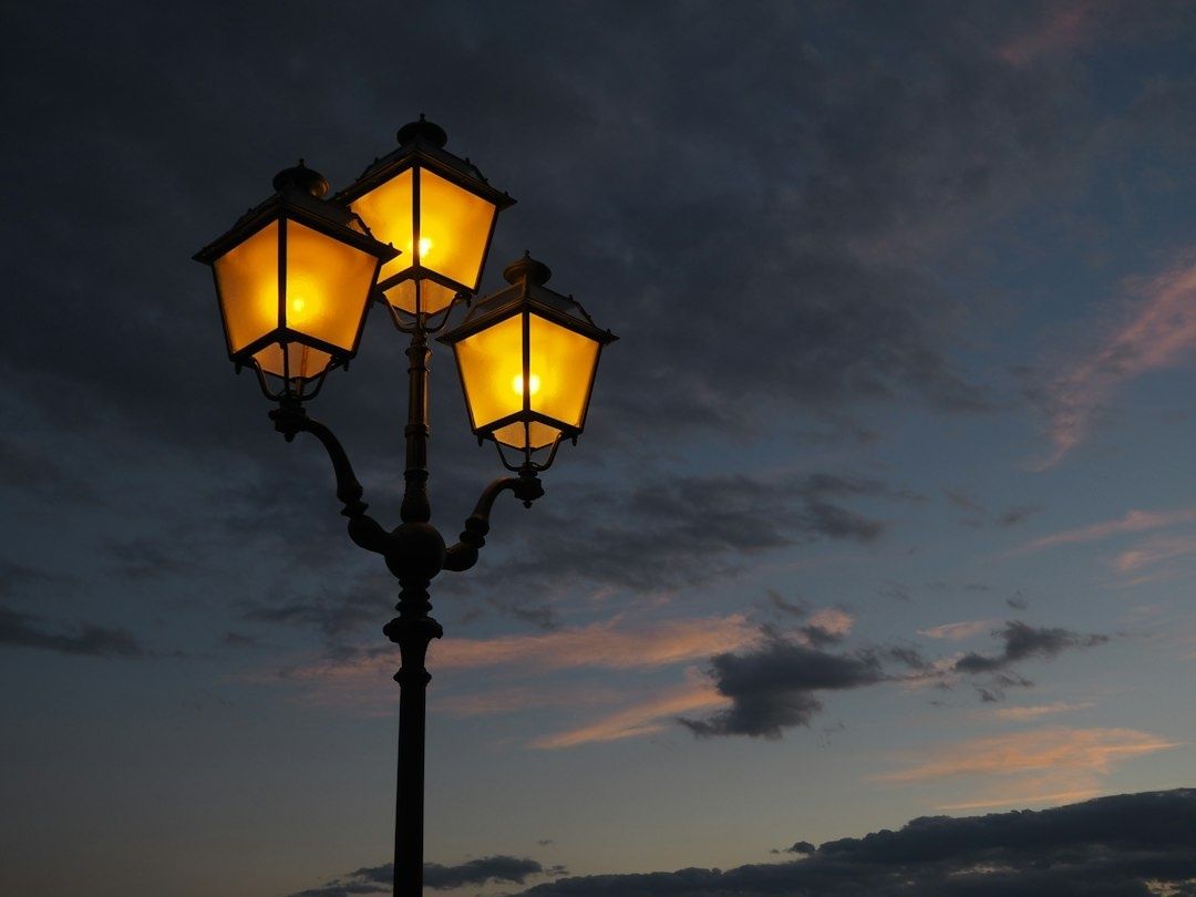 Dreiflammige Straßenlaterne leuchtet warm vor dem dunklen Abendhimmel
